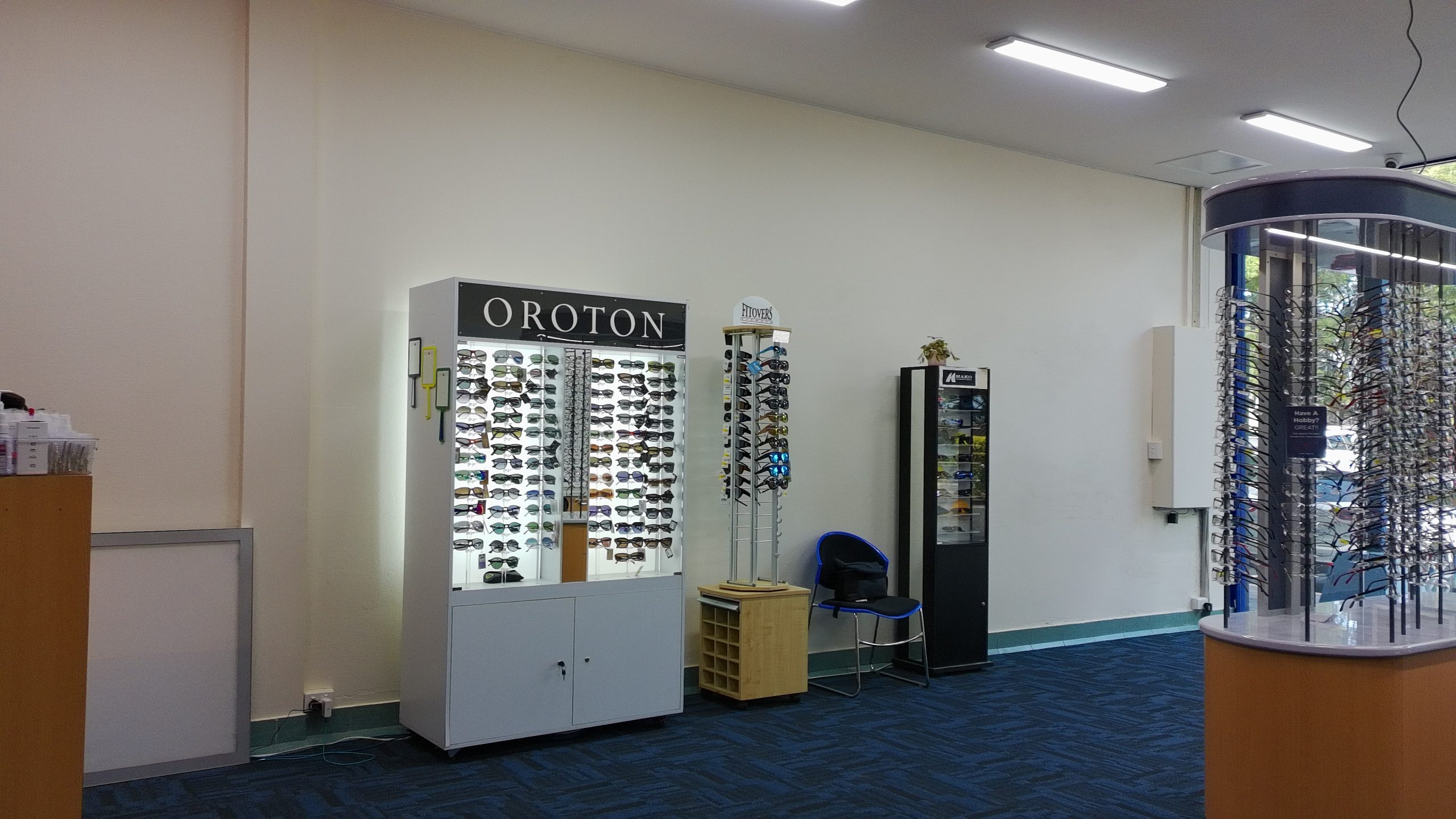 default - The Optical Superstore Interior of an eyewear store with sunglasses displayed on wall and freestanding racks under bright ceiling lights