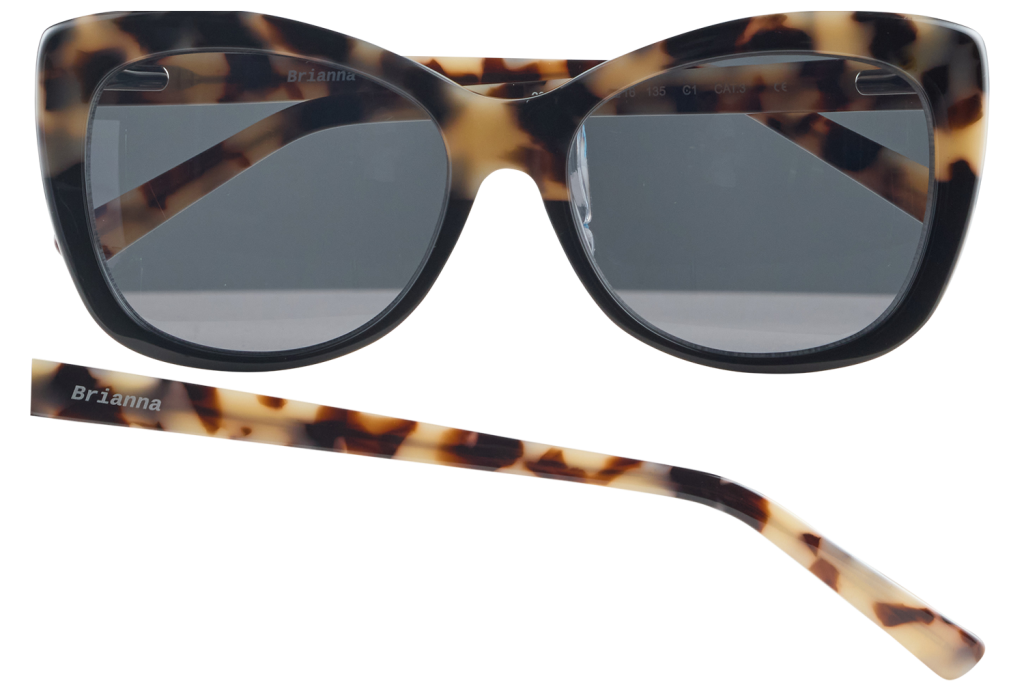 Tortoiseshell sunglasses with dark gray lenses; the name 'Brianna' is printed on the frame and a matching temple lies nearby.