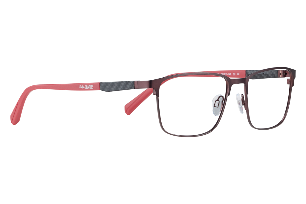 Close-up of red-framed eyeglasses with a black carbon-fiber temple detail, resting on a white surface; brand Ralph Charles visible on the arm.