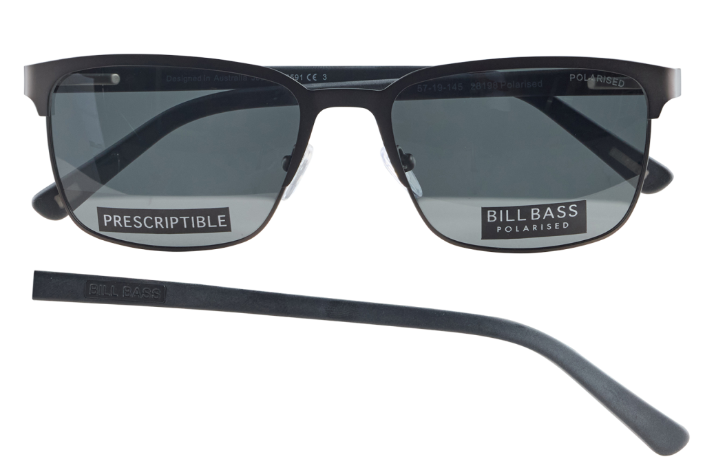 Pair of black rectangular sunglasses with dark lenses, labeled BILL BASS POLARISED and PRESCRIPTIBLE on the lenses, plus a separate black temple piece lying nearby.