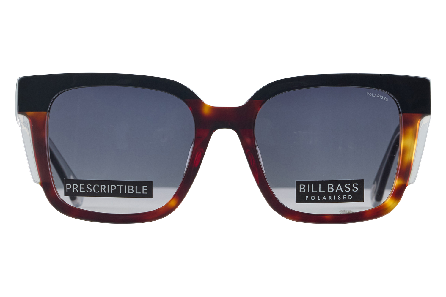 Close-up of tortoiseshell sunglasses with dark lenses and brand stickers reading PRESCRIPTIBLE and BILLBASS POLARISED across the lenses.