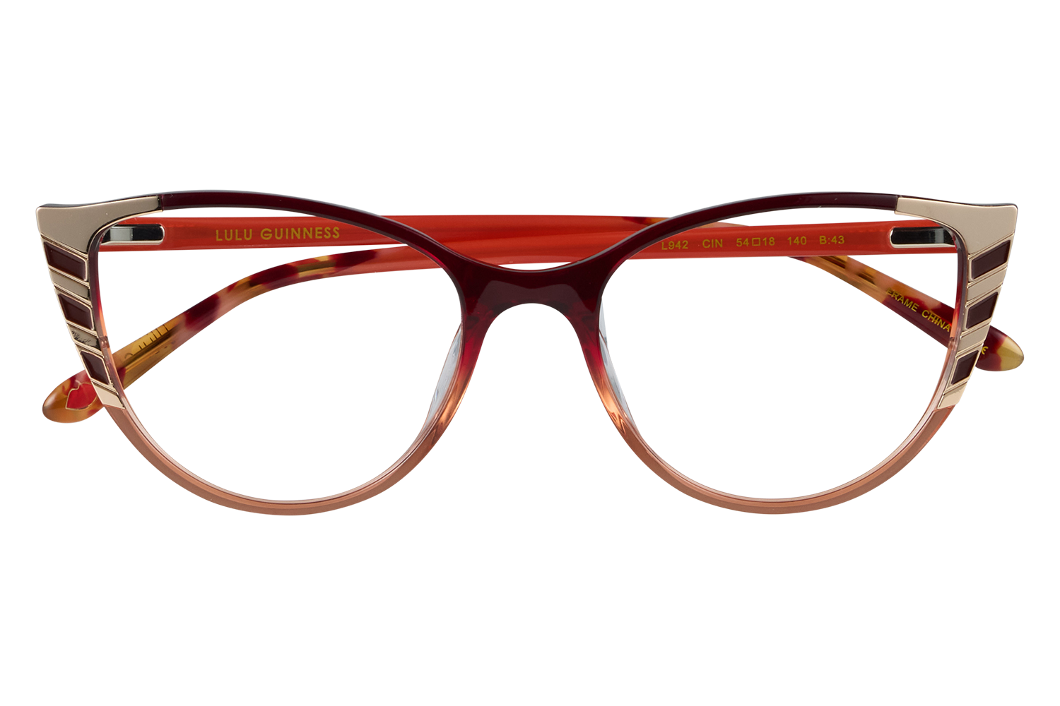 Red-framed glasses with gold accents on the temples, resting on a clear stand for display purposes (LULU GUINNESS branding visible).
