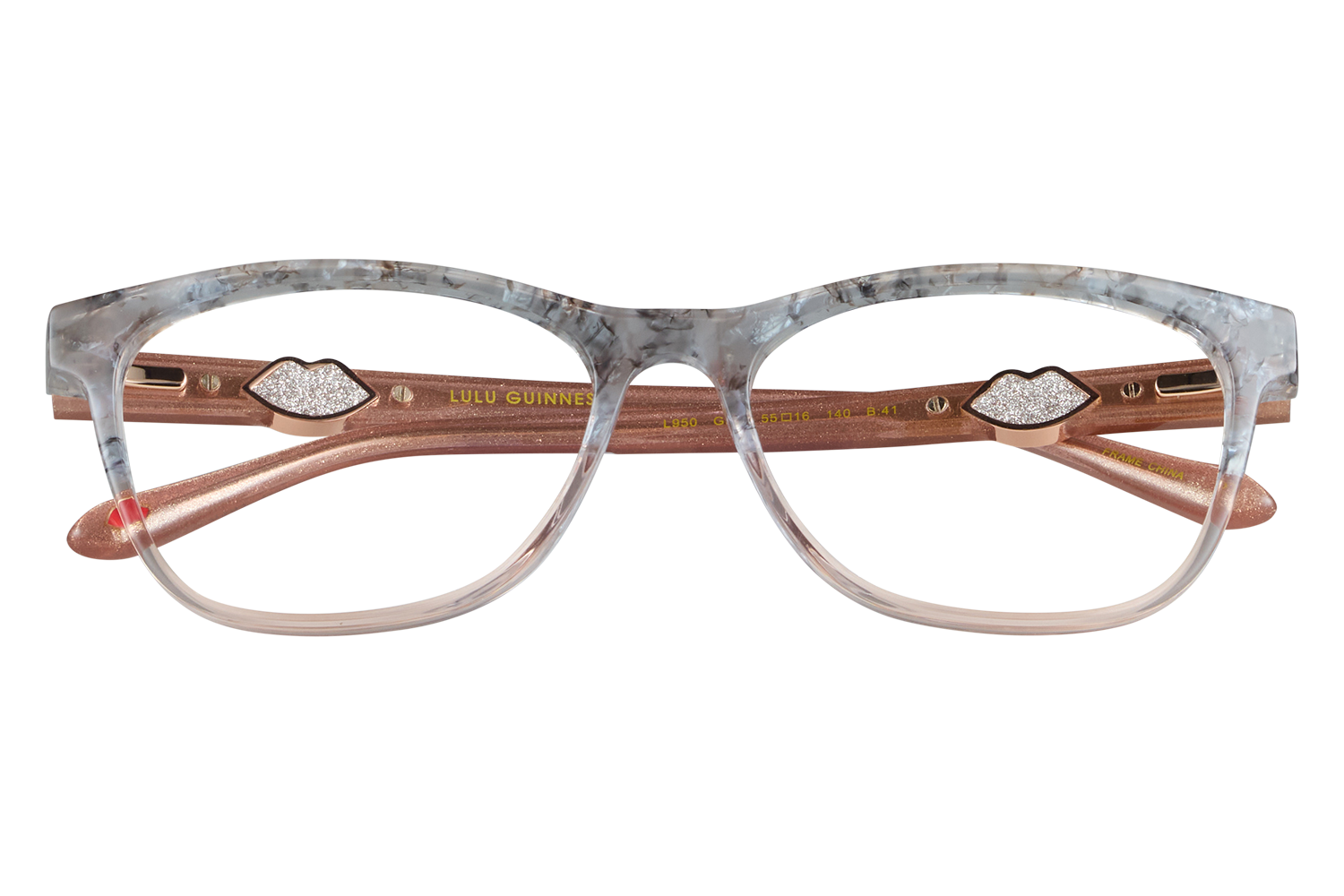 Pink marbled-frame eyeglasses with bronze temples and lip-shaped decorative accents resting on glass blocks, displayed on a gray background.
