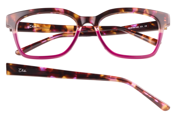 Tortoiseshell eyeglasses with pink frames and matching temple pieces laid apart, stylish chunky design with a signature on the arm.