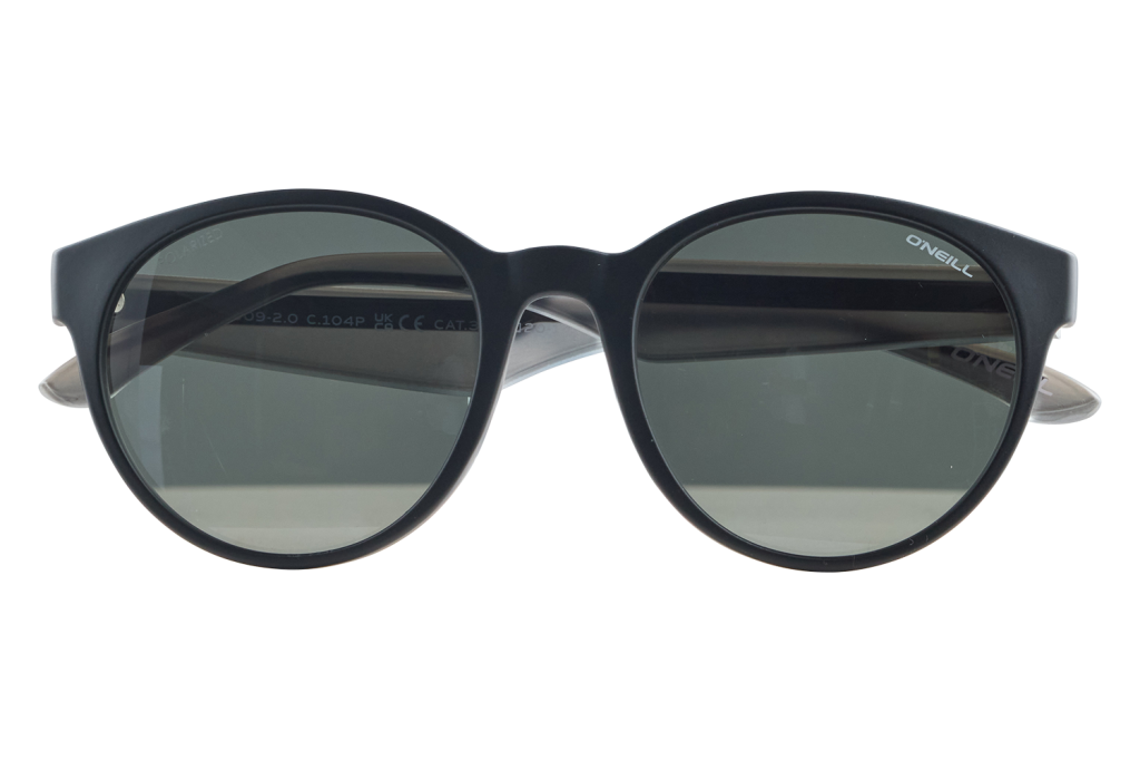 Black round-frame sunglasses with dark green lenses displayed on a small clear stand; brand 'O'Neill' visible on the right temple side.